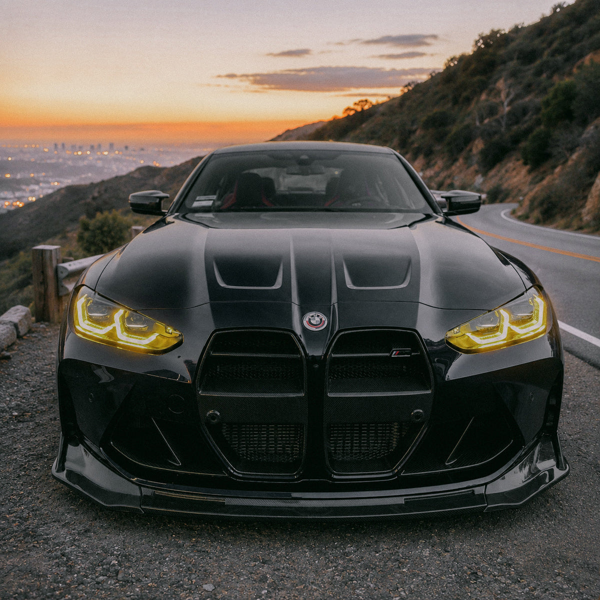 AlpineX Dynamics V Style 3 Piece Carbon Fiber Front Lip installed on a BMW G8X M3 M4, featuring a glossy carbon fiber finish and an aggressive three-piece aerodynamic design.